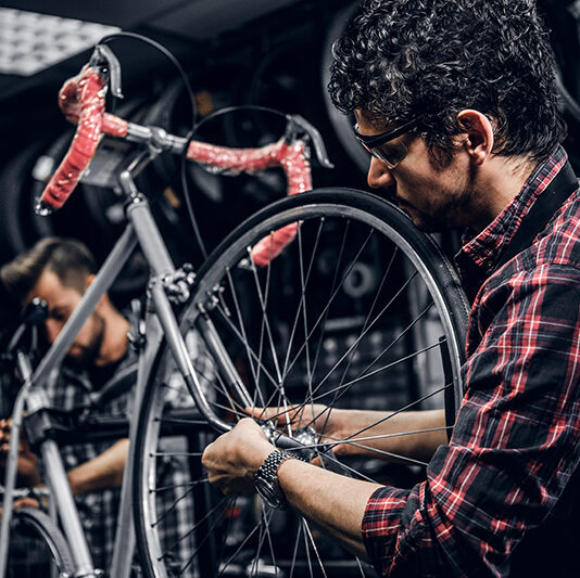 two-attractive-repairmans-are-fixing-broken-bicycle-their-dark-workshop